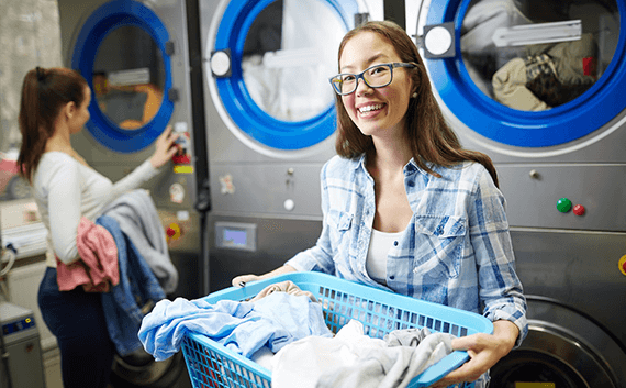 コインランドリーで洗濯かごを抱えて笑う女性
