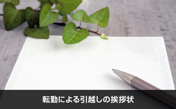 木目調の机の上に置かれた便箋とボールペンと観葉植物